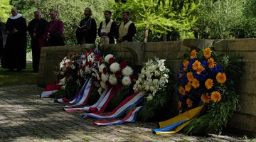 Blick auf die Internationale Kriegsgräberstätte mit Vertretern verschiedener Konfessionen im Hintergrund